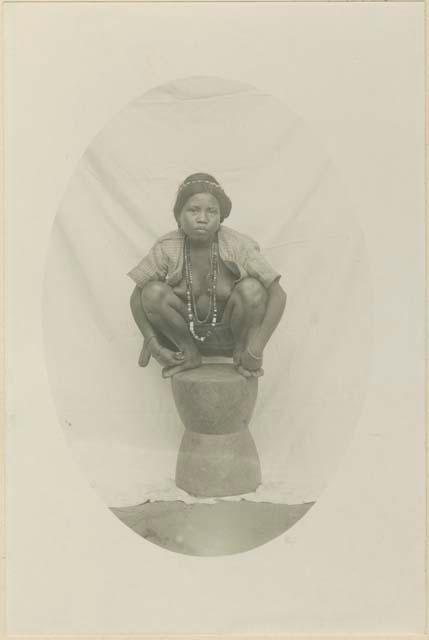 Kalinga woman posed squatting on a rice mortar