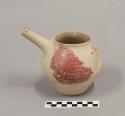 Ceramic vessel with straight spout, red burnished exterior surface, and concretions on surface