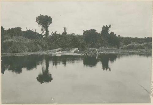 Ilocono women washing clothes in river; fish traps