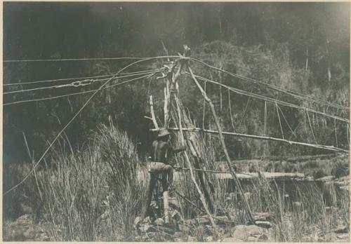 Man climbing bridge made of rattan and poles