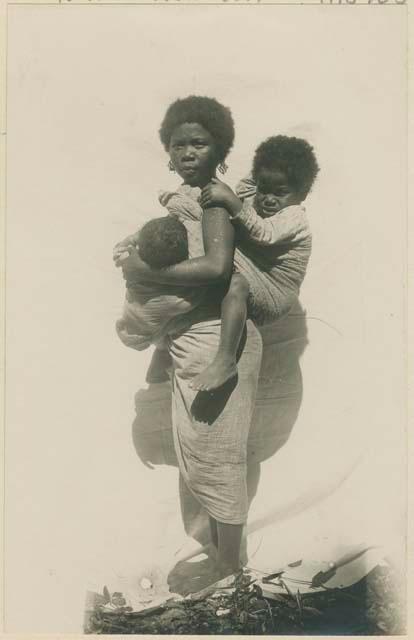 Woman nursing one child and carrying another