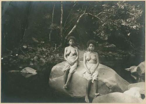 Two woman resting on a rock in mountain stream