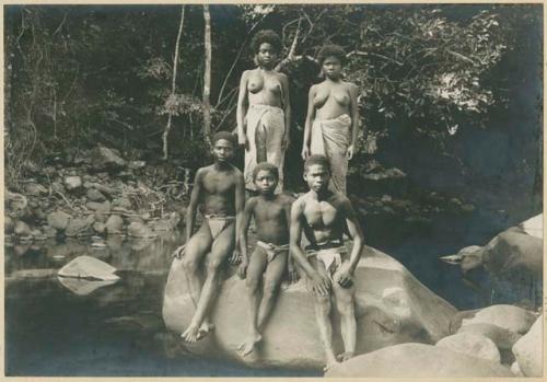 Adults resting on rock in mountain stream