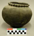 Ceramic vessel, scalloped neck, plain black body.