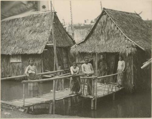 Four Moro women and one man in front of two houses