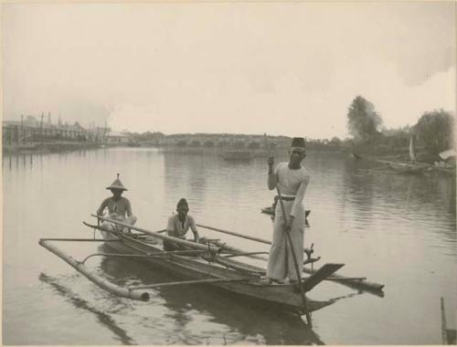 Three Moro men in wooden canoe on water