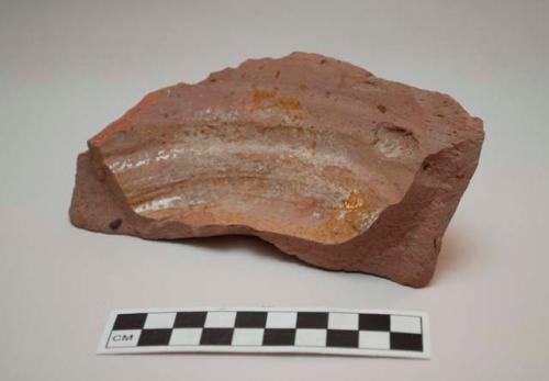 Sherd of base of vessel, red clay, remnants of yellow glaze on interior