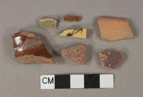 5 Brown slip glazed redware vessel body fragments, 2 yellow slip-glazed earthenware, buff paste, dark brown slip decorated