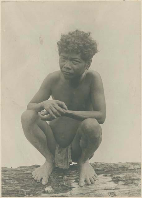 Man squatting on a log