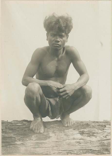 Mangyan man squatting on a log