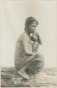 Profile of Mangyan woman squatting on a log