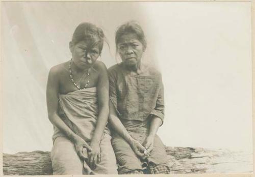 Two Mangyan women sitting on a log