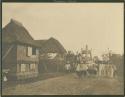 Thatched house, bearers with carriage