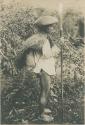 Tinguian man with rain hat, rain coat, and war lance