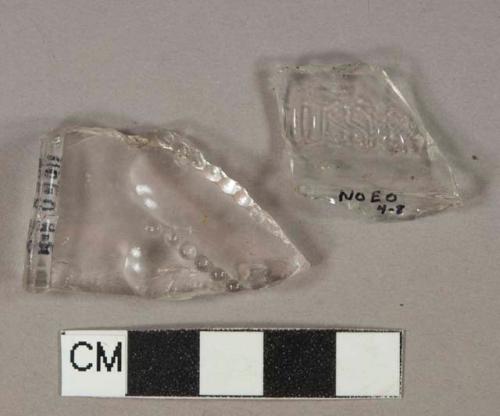 Colorless glass vessel body fragments, 1 fragment with molded lettering "[...]USK[...]", 1 fragment molded decoration