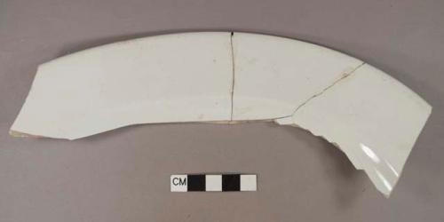 Undecorated whiteware vessel rim fragment, likely platter