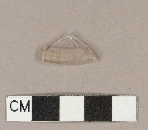 Colorless glass fragment with rolled edge; appears to be base of a stemmed vessel