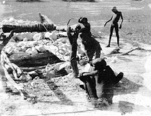 Boys sitting and standing next to a well