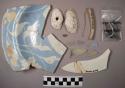 Portion of blue and white plate, with scalloped rim. pipe fragments shells, na
