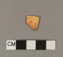 Orange-stained porcelain body sherd with red and black transfer printed maker's mark
