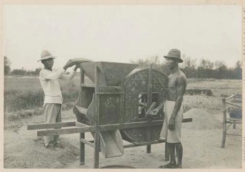 Filipino men fanning mills for rice
