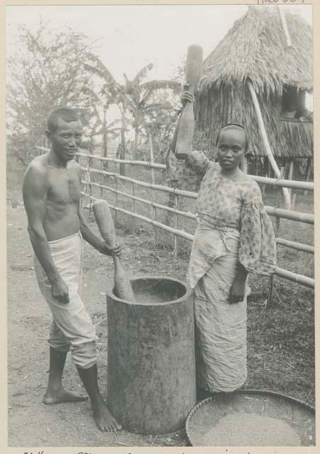 Man and woman pounding rice with pestles