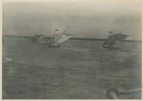 Small boats running to shore ahead of barge