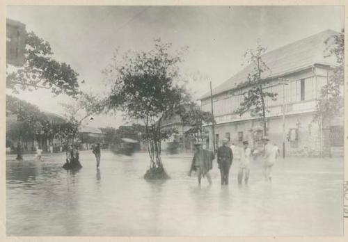 People standing in flooded street in Manila after typhoon