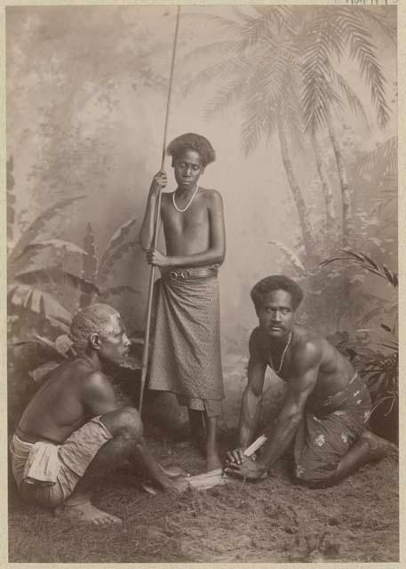 Studio staged portrait of three men making a fire