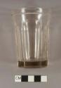Colorless glass fluted tumbler with ridged line below rim. Has makers mark on bottom of Capstan Glass Company with letter "S"