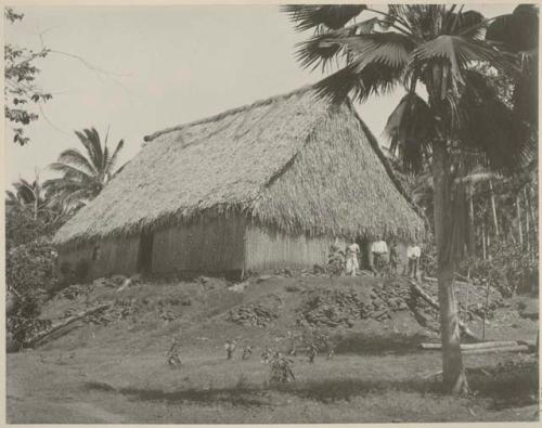 People standing in front of thatched house