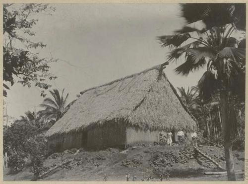 People standing in front of thatched house