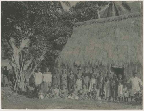 Group of people in front of thatched structure