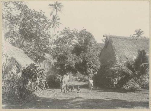 Man and woman with children between thatched structures