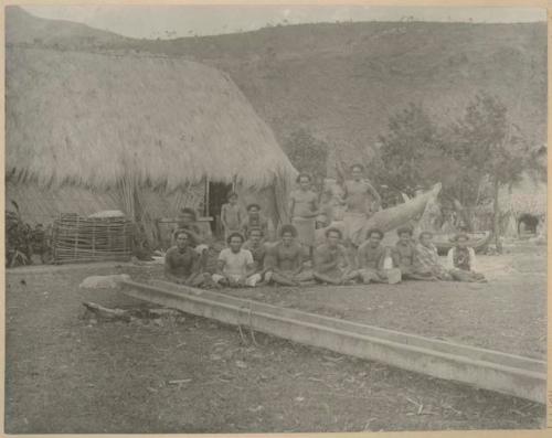 Group of people with dog between long trough and house