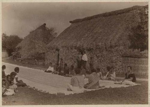 People sitting along Tapa cloth