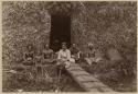 Men and boy with baskets in front of house