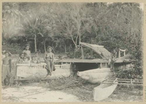 Group of people next to outrigger canoes