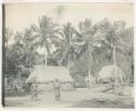 Two men in front of village structures and palms