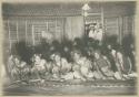 Women sitting on a mat, dancing, with onlookers including Western sailors in the doorway