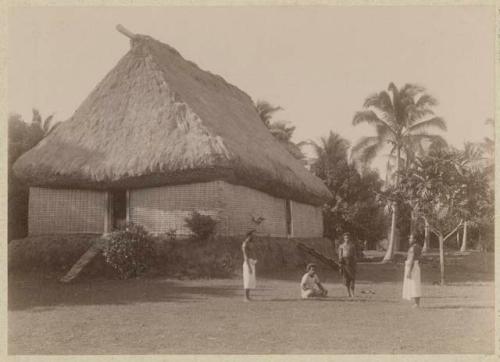 People outside thatched house