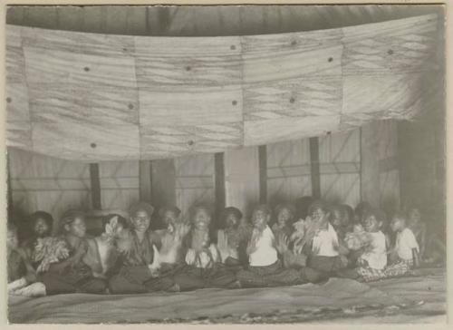 People seated and waving hands indoors