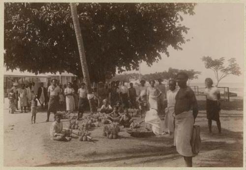 Group of people at market, with pineapples on sale
