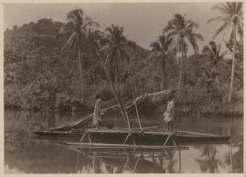 Two men standing in double canoe on Tamavua River