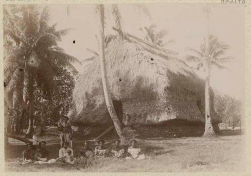 Group of people outside thatched structure