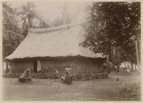 Group of people outside thatched structure