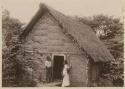 Couple and baby in front of thatched house