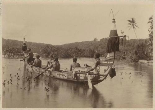 People rowing ornamented canoe