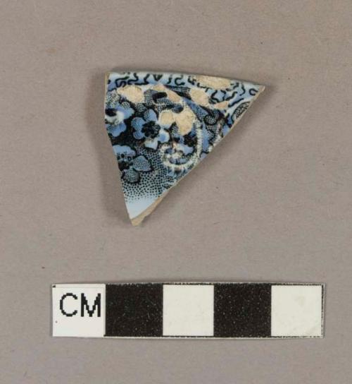 Blue-tinted, black transfer printed whiteware rim sherd with molded decoration