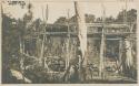 Wooden platform on stilts, possibly pier, with structure in the background, possibly pile dwelling